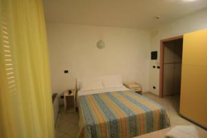里米尼海滩天堂住宅酒店的小卧室配有一张带彩色毯子的床