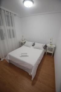 格拉纳迪利亚德亚沃纳El Médano, apartamento céntrico y cerca del mar的白色卧室配有一张大白色床和两张桌子