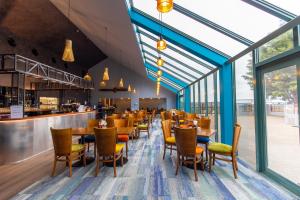 汉密尔顿JetPark Hamilton Airport New Zealand的一间带桌椅的餐厅和一间酒吧