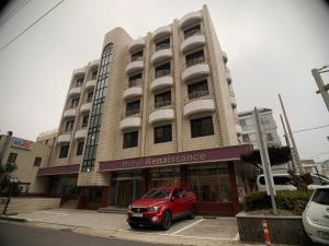 济州市Jeju Renaissance Hotel的停在大楼前的红色汽车
