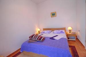 索布拉Apartments Filipović的一间卧室配有一张带紫色床单的床和两盏灯。