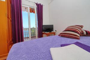 索布拉Apartments Filipović的一间带紫色床的卧室和一个阳台