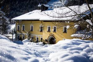 翁特陶埃恩格斯族泊斯特费瑞酒店的雪中的一个黄色房子,有雪覆盖的场地