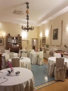 锡拉库扎多莫斯迈瑞旅馆的餐厅配有白色的桌椅和吊灯