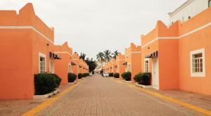 塞拉莱Star Emirates Garden Villas的一条空的街道,有橘色的建筑和棕榈树