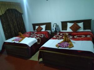 努沃勒埃利耶雅芳农场度假别墅旅馆的配有红色和白色床单的客房内的两张床
