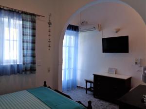 锡基诺斯岛Ostria Studios - Spilia的一间卧室设有一张床、一台电视和一个窗口。