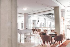 顿河畔罗斯托夫唐广场国会酒店 的大堂配有白色钢琴和桌椅