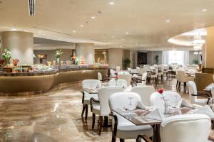 麦加Millennium Makkah Al Naseem的一间设有白色桌椅的餐厅和一间酒吧