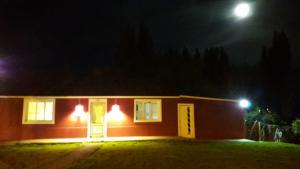 埃尔卡拉法特Aguilar House Hostel B&B的夜晚,有月亮在后面的小房子