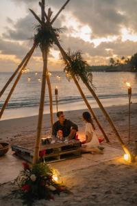 Maninoa辛纳雷礁水疗度假酒店的坐在海滩桌子上的男人和女人