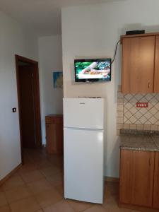 梵蒂冈角Villetta sul mare的厨房配有白色冰箱,墙上配有电视