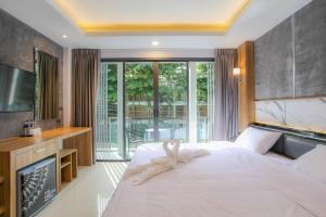 卡塔海滩The Mantra Hotel Kata Noi的卧室配有一张白色大床和电视。