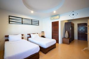 苏林海滩苏林度假屋的一间卧室设有两张床,墙上挂着一个时钟。
