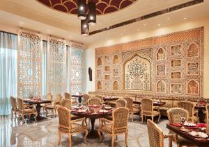 阿格拉Taj Hotel & Convention Centre, Agra的一间带桌椅的用餐室和一面墙