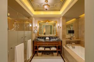 新德里新德里里拉宫殿酒店的浴室配有盥洗盆、镜子和浴缸