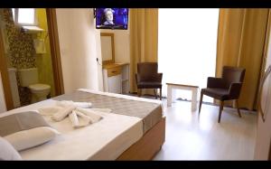 恰纳卡莱GÜVEN HOTEL的一间卧室配有一张床、两把椅子和一台电视