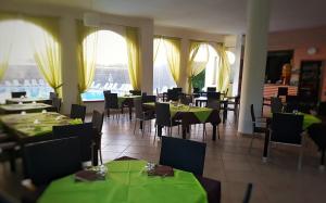 维耶斯泰Villaggio Alba Chiara的餐厅设有绿色桌椅和窗户。