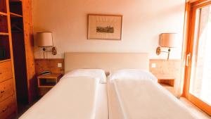 弗利姆斯Hillsite Smart Hotel Flims的一间卧室设有两张白色的床和窗户