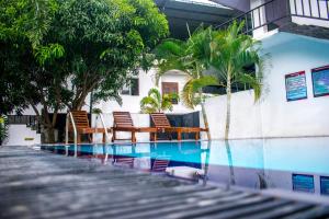 波隆纳鲁沃Lion Resort的一座带椅子和棕榈树的游泳池,毗邻一座建筑
