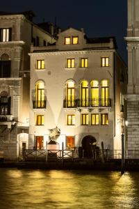 威尼斯Palazzina Grassi的一条白色的大建筑,在河边设有明亮的窗户