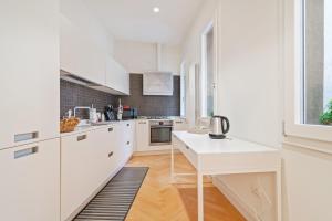 帕多瓦San Fermo Luxury Apartment的白色的厨房配有白色的橱柜和桌子