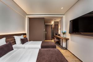 塞萨洛尼基Imperial Plus Urban Smart Hotel Thessaloniki的配有一张床和一台平面电视的酒店客房