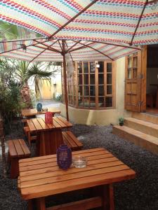 伊基克Backpacker's Hostel Iquique的庭院设有木桌和雨伞。