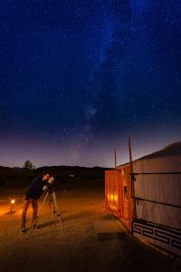二十九棕榈村28 Palms Ranch的一个用三脚架拍夜空照片的人