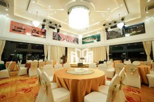 巴淡岛中心绿色玫瑰酒店的宴会厅配有桌子和白色椅子