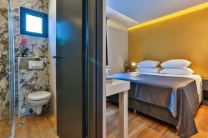 波德戈里察M酒店的一间卧室配有一张床,浴室设有卫生间