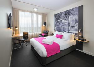 墨尔本墨尔本蒂埃里街美居酒店的酒店客房配有一张带粉红色毯子的大床