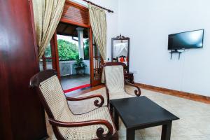 本托塔Chami Villa Bentota的客厅配有两把椅子、一张桌子和电视