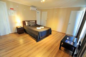 塞图巴尔Suites & Apartments - DP Setubal的一间卧室配有一张床,铺有木地板