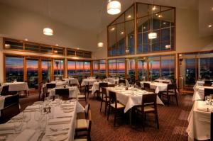 圣雷莫菲利普岛银光清水度假村的餐厅设有白色的桌椅和窗户。