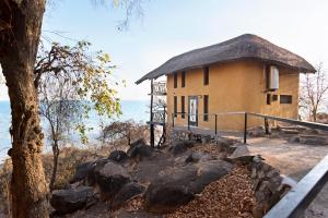 SengaSafari Beach Lodge的水边有茅草屋顶的建筑