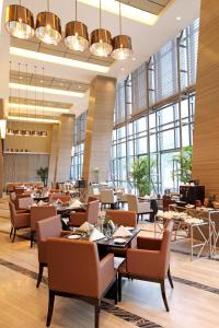 济南济南阳光壹佰雅高美爵酒店的餐厅设有桌椅和大窗户。