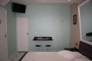 瓜鲁柳斯Motel Emoções de Guarulhos的一间卧室配有一张床和两张凳子