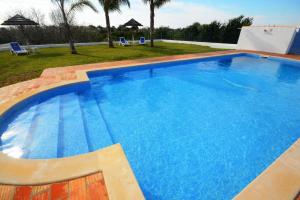 阿尔坎塔里利亚Villa Casa das Amendoeiras的一座带两把椅子的大型蓝色游泳池,位于庭院内