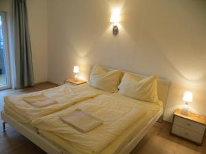 萨尔茨堡City Apartment Amadeus的卧室配有白色床,墙上有两盏灯