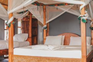 Ruaha National ParkMabata Makali Luxury Tented Camp的一间卧室配有两张带白色枕头的天蓬床