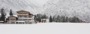 皮勒尔湖畔圣乌尔里希Hotel Landhaus Tirolerherz的一座大房子,后面有雪覆盖的山
