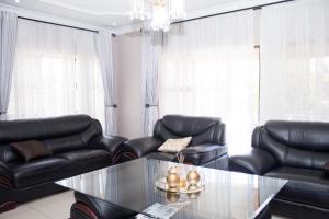 哈拉雷Villa Prince的客厅配有黑色真皮座椅和玻璃桌