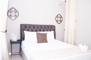 哈拉雷Villa Prince的一间卧室配有一张白色的床和黑色床头板
