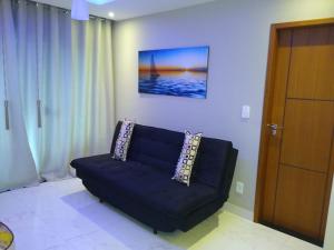 卡波布里奥Apartamento Praia do Forte VIP的客厅里的一张黑色沙发,墙上挂着一张照片