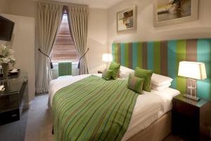 伦敦新林登酒店的一间卧室配有一张带绿色和白色毯子的床