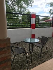 莫阿尔博阿ANCHORAGE INN Moalboal的庭院设有两把椅子、一张桌子和一扇窗户。