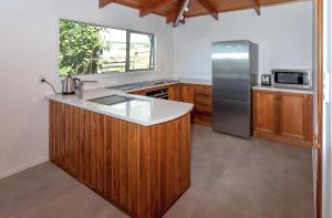 哈海Hahei Views的厨房配有木制橱柜和不锈钢冰箱。