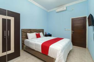 BebekoRedDoorz Syariah @ Mora Garden Bungo的一间卧室配有一张带红白毯子的床