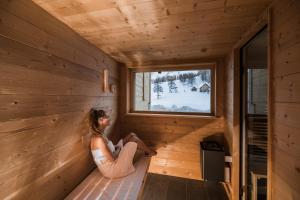 塞斯托Rotwandwiesen Chalets SKI IN/OUT - 1900mt的一位女士坐在小木屋内,眺望窗外